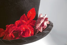 Carica l'immagine nel visualizzatore di Gallery, Cappello artigianale made in Italy in morbido feltro velour di lapin neroguarnito da una coppia di rose rosse di velluto e dall'ala bordata torçon da un prezioso nastro di velluto nero. Top hat tra i più iconici e amati da sempre