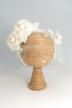 Carica l'immagine nel visualizzatore di Gallery, Cerchietto con camelie in tessuto di fibra vegetale avorio guarnite da veletta bianca con moschina. Su ordinazione, personalizzabile.
